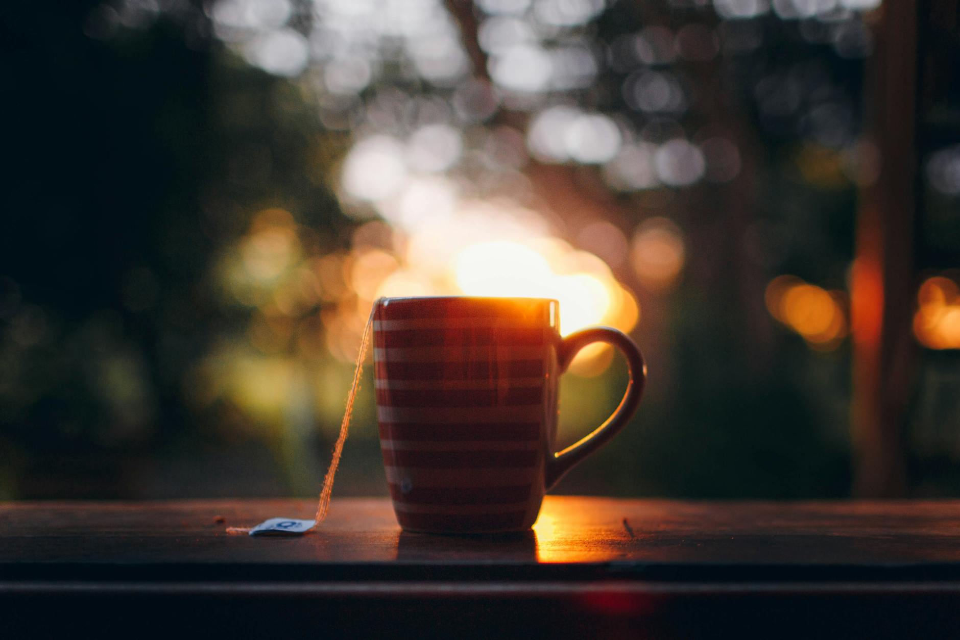 cup of hot tea on wooden windowsill during sundown