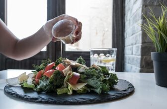 person pouring dip on vegetable salad